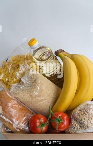 Verschiedene Lebensmittel in der Kartonbox mit Kopierplatz. Spende Lebensmittel in der Box. Obst, Öl und Getreide Stockfoto