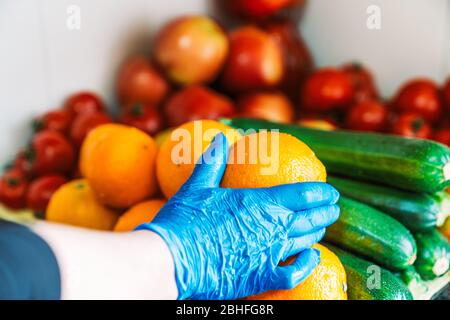 Gereinigtes und desinfiziertes Obst und Gemüse auf der Oberseite der Küche Marmor.Frau Reinigung von Obst und Gemüse, um Coronavirus mit blauem Latex zu verhindern Stockfoto