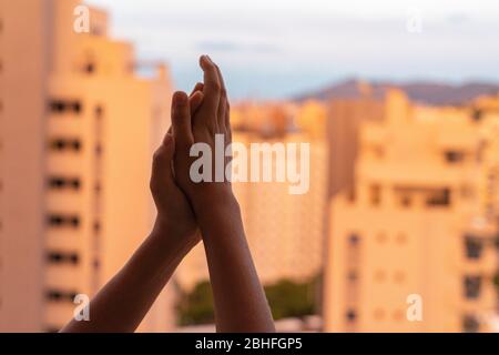 Kind klatscht Hände, applaudieren vom Balkon, um Ärzte, Krankenschwestern, Krankenhausmitarbeiter während der Coronavirus-Pandemie Quarantäne zu unterstützen Stockfoto