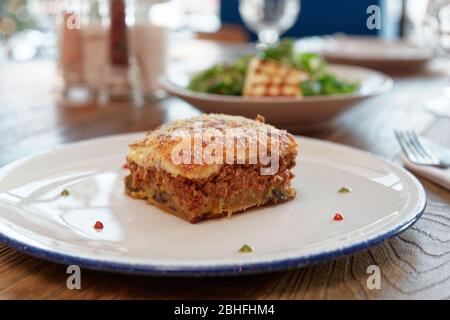 Moussaka und gebratener Feta-Käse, traditionelle griechische Küche, auf dem Tisch Stockfoto