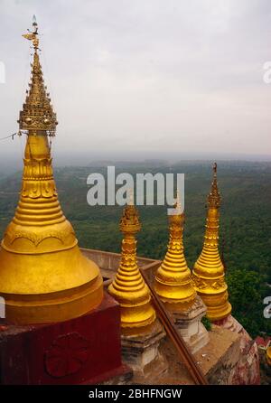 Goldfarbene Stupas auf dem Pilgerort Mount Popa mit den üppigen Wäldern Myanmars im Hintergrund Stockfoto