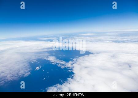 Luftaufnahme aus einem Flugzeugfenster, das über Wolken und dem Atlantik fliegt Stockfoto