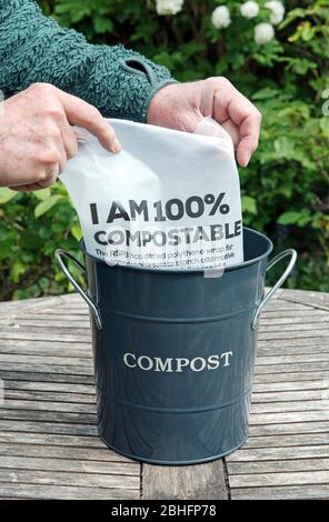 Man Futter Kompostbehälter mit kompostierbaren Magazin Verpackung oder Verpackung aus Kartoffelstärke sagen "Ich bin 100% kompostierbar" auf Gartentisch. Keine Verschwendung Stockfoto