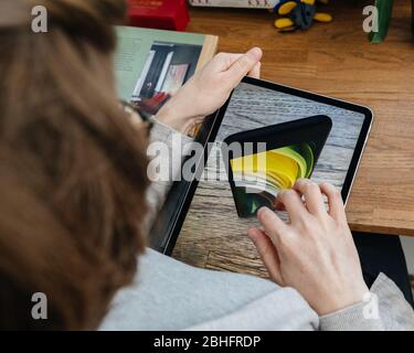 Paris, Frankreich - 16. April 2020: Neugierige Frau auf Apple Computers Internet-Website auf iPad Pro Tablet neue iPhone SE Inspektion auf Augmented Rea Stockfoto