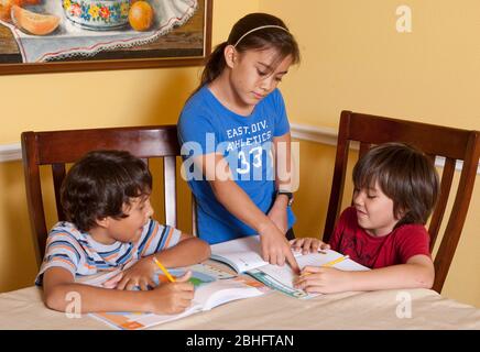 Austin Texas, USA, 2012: Ein 10-jähriges japanisch-amerikanisches Mädchen hilft ihrem 8-jährigen Bruder (rechts) und hispanischen Freund zu Hause bei der Arbeit. ©Marjorie Kamys Cotera/Daemmrich Photography Stockfoto