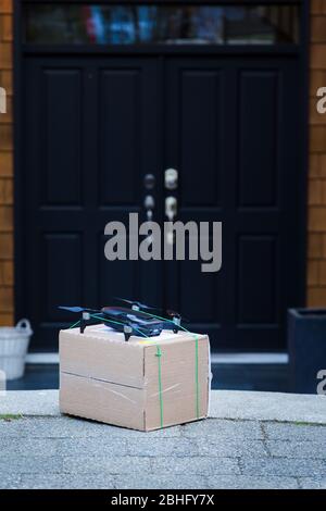 Ein Paket, das vor einer Residenz sitzt, die von einer autonomen Drohne geliefert wurde. Stockfoto