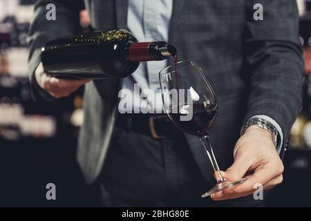 Sommelier des Kellners, der Rotwein in Glas gießt Stockfoto