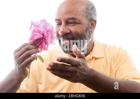 Afroamerikanischer Mann mit einer lila Rose auf weißem Hintergrund. Romantisches Konzept der Liebe, valentinstag oder Muttertag Stockfoto