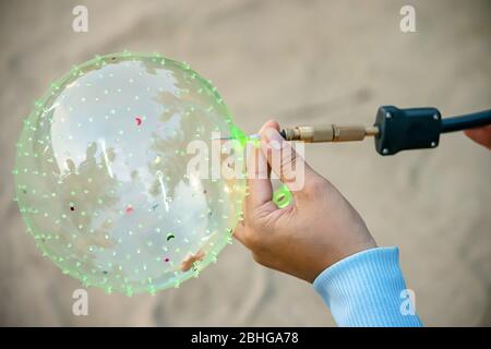 Hand mit einem Ballon und mit einer Nadel aufblasen. Stockfoto