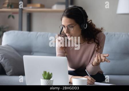 Fokussierte Millennial weibliche Studentin beobachten Online-Bildungs-Webinar, Notizen schreiben. Stockfoto