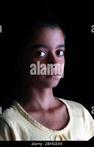 Porträt eines kleinen indischen Mädchens mit kurzen Haaren. Schönes Auge eines Kindes auf schwarzem Hintergrund. Dramatischer Blick eines kleinen Mädchens in Indien. Stockfoto