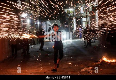 Gaza-Stadt, Palästina. April 2020. Ein palästinensischer Jugendlicher schwingt ein selbstgemachtes Feuerwerk, während er die erste Nacht des Heiligen Monats Ramadan im Lager Jabalia im nördlichen Gazastreifen feiert: Von abgebrochenen iftar (Fast Breaking) Festen bis zu unterbrochenen Moschee-Gebeten, Muslime im gesamten Nahen Osten sind auf einen düsteren Monat des Fastens Ramadan vorbereitet, da die Bedrohung durch die COVID-19 Pandemie andauert. Der heilige Monat des Fastenmonats der Muslime Ramadan ist eine Zeit der Selbstreflexion und der Sozialisierung. Gläubige fasten von Sonnenaufgang bis Sonnenuntergang und versammeln sich dann um eine Familie oder Gemeinschaft für ein Essen jeden Abend Stockfoto