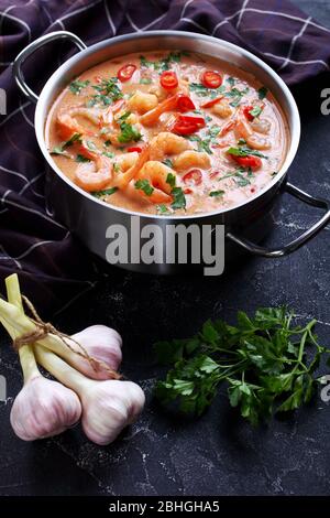 Tom Yum Suppe, tom Kha Suppe in einem Topf auf einem Betontisch mit braunem Tuch und Löffel, vertikale Ansicht von oben Stockfoto