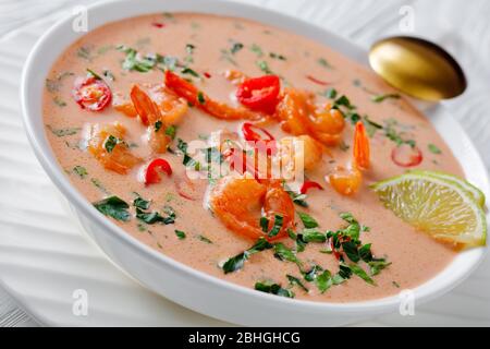 Nahaufnahme von Tom Yum Suppe, tom Kha Suppe in einer weißen Schüssel auf einem Holztisch, horizontale Ansicht von oben Stockfoto