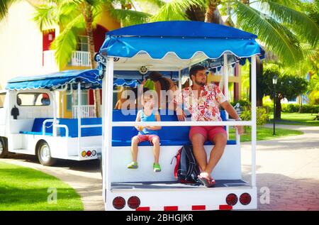 Glückliche Familie, die den Urlaub während der Fahrt im Auto durch die Hotelanlage genießt. Transportservice Stockfoto