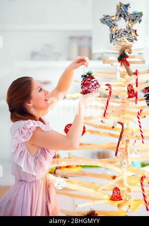 Junge Frau Dekoration außergewöhnliche, umweltfreundliche weihnachtsbaum aus Zweigen, Winterferien Stockfoto