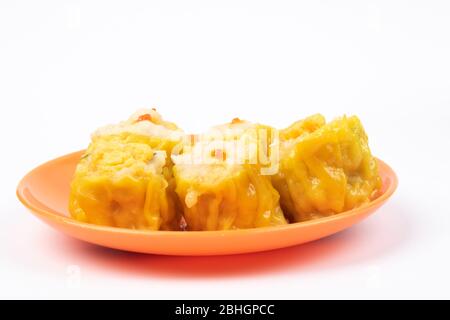 SIU Mai - Chinesische gedünstete Schweinefleischknödel auf Teller isoliert auf weißem Hintergrund. Stockfoto