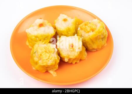 SIU Mai - Chinesische gedünstete Schweinefleischknödel auf Teller isoliert auf weißem Hintergrund. Stockfoto
