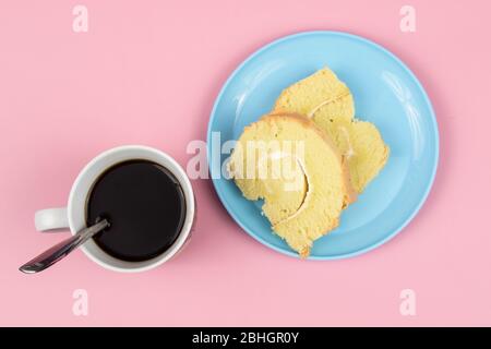 Scheibe Schweizer Rollkuchen mit Tasse Kaffee auf rosa Hintergrund. Stockfoto