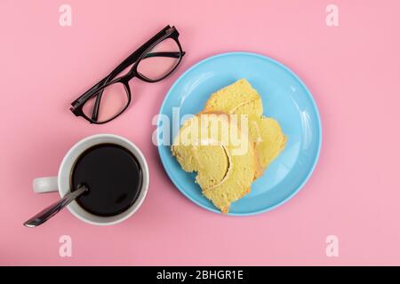 Brillen Gläser, Slice of Swiss Roll Cake und Tasse Kaffee auf rosa Hintergrund. Konzept Für Eine Teepause Stockfoto