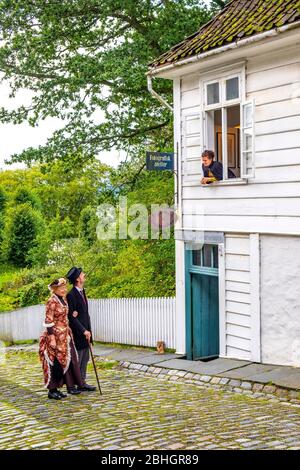 Bergen, Hordaland / Norwegen - 2019/09/06: Rekonstruierte norwegische Stadtstraße aus dem 19. Jahrhundert mit Holzhäusern und inszenierten sozialen Szenen in Old Bergen Mus Stockfoto