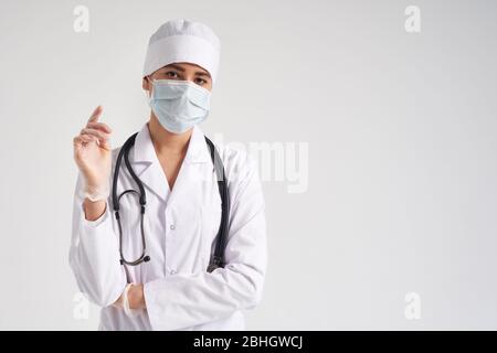 Junger Arzt trägt chirurgische Handschuhe und Gesichtsmaske, Studio über weißem Hintergrund mit Kopierraum erschossen Stockfoto