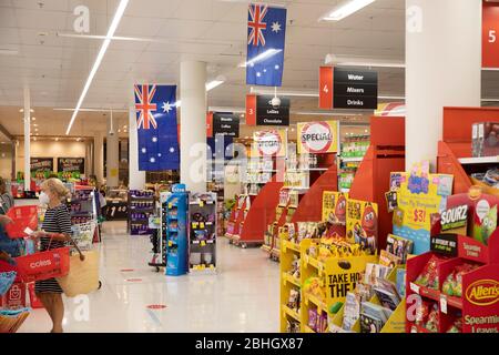 COVID-19 Frau mit einer Facemask, als sie in einem Supermarkt in Sydney Lebensmittel kauft, die stolz australische Flaggen tragen Stockfoto
