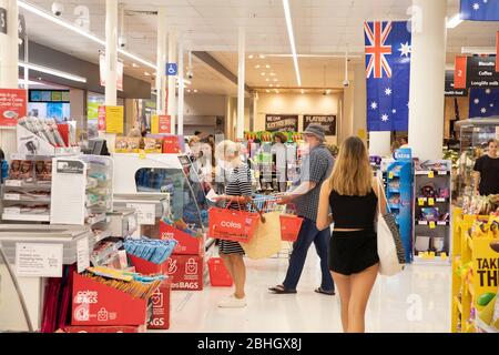 Australischer Supermarkt und Frau an der Kasse trägt Gesichtsmaske aufgrund von covid 19, Sydney, australische Flagge im Geschäft Stockfoto