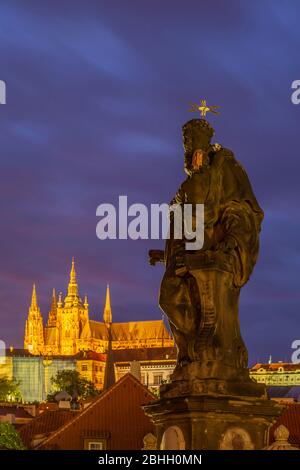 Die Prager Burg und die Statue des Antonius von Padua erleuchteten nachts auf der Karlsbrücke in Prag. Stockfoto