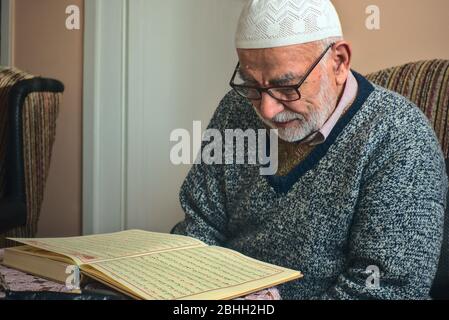 Ältere türkische muslimische männliche rezitieren das heilige Buch des Islam, Koran im Ramadan Monat vor iftar Stockfoto