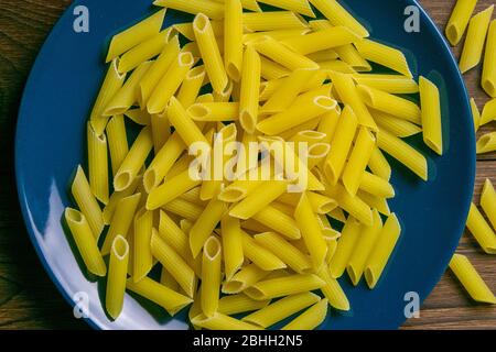 Pene Lisce Pasta in blauer Platte auf dunklem Holzhintergrund. Von oben Stockfoto