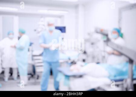 Abstrakter medizinischer verschwommener Hintergrund des OP, Patient liegt auf dem Tisch, Ärzte arbeiten Stockfoto