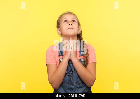 Porträt der Bitte kleine Mädchen in Denim Overalls aufschauen beten zu gott mit flehenden Augen, fragen herzlich, machen Kindheitserwünsche und Hoffnung. ich Stockfoto