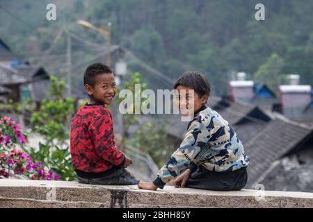 (200426) -- MENGHAI, 26. April 2020 (Xinhua) -- Kinder spielen draußen im Dorf Manbansandui im Dorf Mannan im Landkreis Menghai, südwestlich von Chinas Provinz Yunnan, 12. April 2020. Weit entfernt in den Bergen des südwestlichen Chinas Yunnan liegt der ehemalige Ort des von Armut geplagten Manbansandui Weilers, wo 17 Haushalte der ethnischen Gruppe Lahu lebten. Im Hinblick auf die Lebensgewohnheiten und Bräuche der Dorfbewohner wurde das Dorf 2009 in ein neues Gebiet an seinen ursprünglichen Standort verlegt, um das Lebensumfeld der Dorfbewohner zu verbessern und die Armut abzuschütteln. Zusätzlich zur infrastr Stockfoto