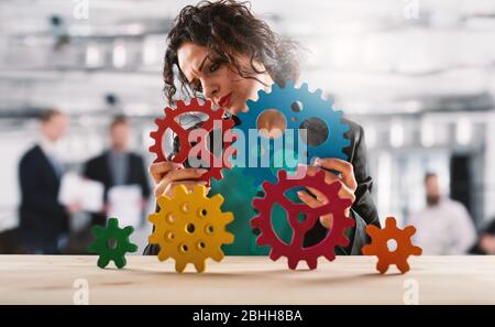 Geschäftsfrau versucht, mit Zahnrädern zu arbeiten. Konzept von Teamwork und Partnerschaft. Stockfoto