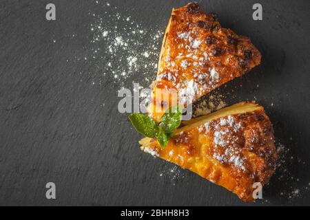 Zwei Stück Quark Kasserolle mit Minzblättern und Puderzucker. Auf einem schwarzen Schiefer-Ständer. Blick von oben Stockfoto