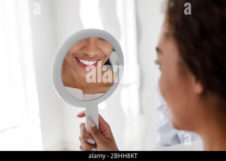 Weißes Lächeln im Spiegel, afrikanisches Mädchen, das Zahnarzt besucht Stockfoto