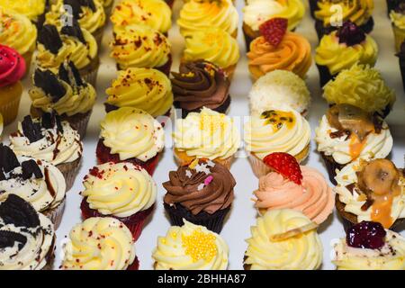 Mattierte Cupcakes stehen zum Verkauf. Abwechslungsreiche Aromen und bunte Dessert-Arten, ideal für Geburtstage, Party, Event, Catering, Bäckerei Konzept Stockfoto