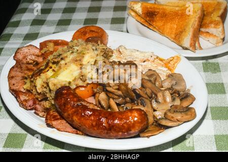 Englisches Frühstück mit Würstchen, gegrillte Tomaten, Pilze, Eier, Speck, Bohnen und Brot. Stockfoto