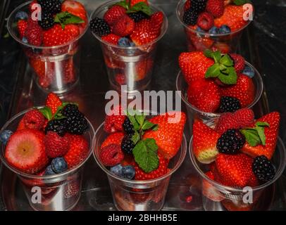 Nahaufnahme von vielen roten Vollfrüchten wie Erdbeeren, Brombeeren, Himbeeren Cocktail-Kunststoff-Tassen in Ladentisch im Sommer Stockfoto