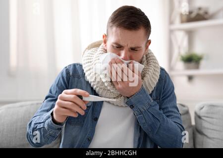 Husten Kerl Überprüfung seiner hohen Körpertemperatur zu Hause Stockfoto