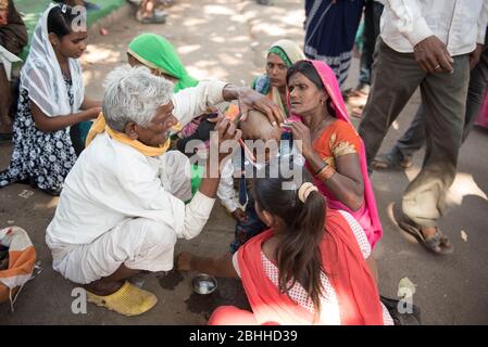 Khajuraho / Indien 24. Februar 2017 Mutter beobachtet den Friseur beim Rasieren ihres Sohnes in khajuraho madhya pradesh Indien Stockfoto