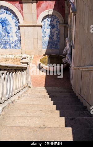 Blaue Fliesen (Azulejos), traditionelle portugiesische architektonische Details, von einem Steinbogen gesäumt. Alte Bordeaux-Fassade. Blick die Treppe hinunter. Teilweise Sonnenschein Stockfoto