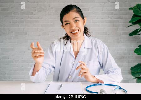 Kamera-Ansicht der Online-Videokonferenz Chat mit asiatischen Ärztin und Patientin während der Diskussion und Diagnose auf Laptop und Blick auf Kamera. Stockfoto