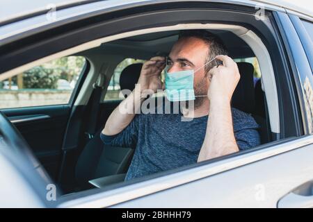 Mann trägt Schutzmaske, um die Infektion von Viren und verschmutzte Luft Ausbreitung Krankheiten in seinem Auto zu vermeiden. Gesundheitswesen, Coronavirus, Influenza Stockfoto