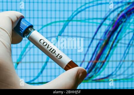 Real-Time PCR-Tests mit COVID-19. Ein Reagenzglas mit einer Probe auf dem Hintergrund von Amplifikationskurven. Stockfoto