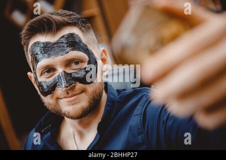Spa Gesichtshautpflege für Männer, Entfernen der schwarzen Holzkohlemaske aus der Nase im Barbershop Stockfoto