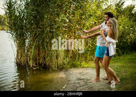 Schönes junges Paar genießen Angeln auf dem See an sonnigen Sommertag Stockfoto