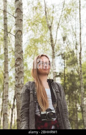 Porträt von attraktiven eleganten jungen Frau mit stilvollen Gläsern auf einem Hintergrund von Bäumen mit goldenen Blättern im Park. Schöne moderne Hipster gi Stockfoto