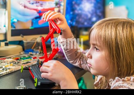 Online Fernstudium zu Hause während der Quarantäne. Ein kleines Mädchen sammelt einen mehrfarbigen Konstruktor an einem Tisch Stockfoto